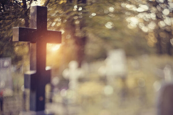 Blurry background with a cross on a grave behind a fencing. It is photographed in the Free-Lensing equipment.