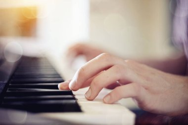 Sentezleyici ve müzisyenin eliyle arka planı bulanık..