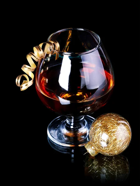 Glass with drink and a Christmas ball. — Stock Photo, Image