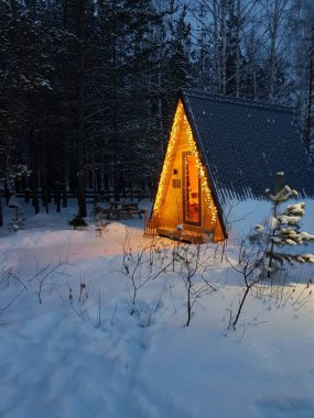 Kışlık ormanda bir çelenkle süslenmiş bir ev.
