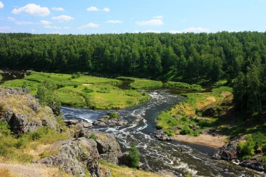 Dağ nehri yeşil kıyıların arasında akıyor.
