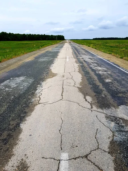 緑のフィールドに空のアスファルト道路 — ストック写真