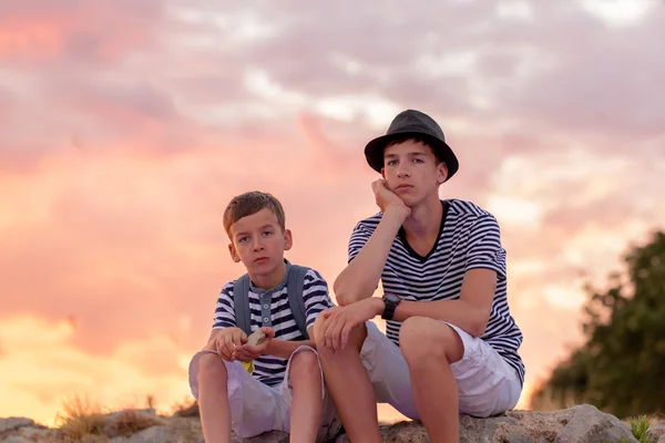 Portrait of two pensive beautiful brothers on backdrop of sunset sky — Stock Photo, Image