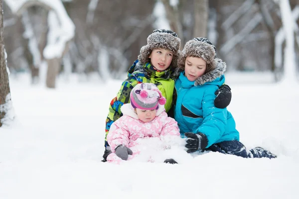 Porträtt av två glada lyckliga pojkar och flicka i Vinterparken — Stockfoto