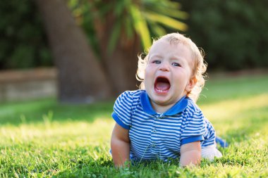 Küçük güzel oldukça mutlu kız çim ve sesler üzerinde yalan
