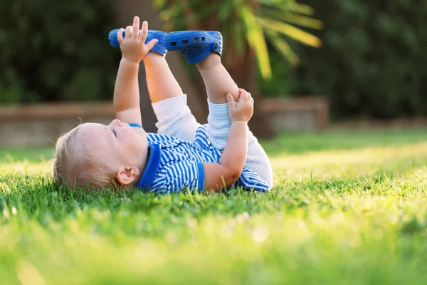 Kleines hübsches, glückliches Mädchen, das im Gras liegt — Stockfoto