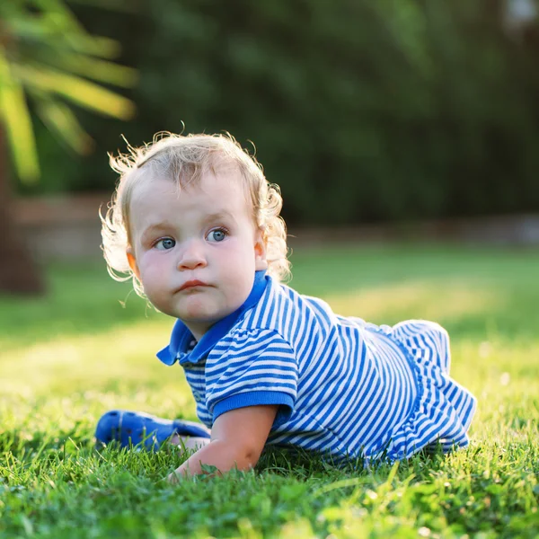 Kleines hübsches, glückliches Mädchen auf Gras sitzend — Stockfoto