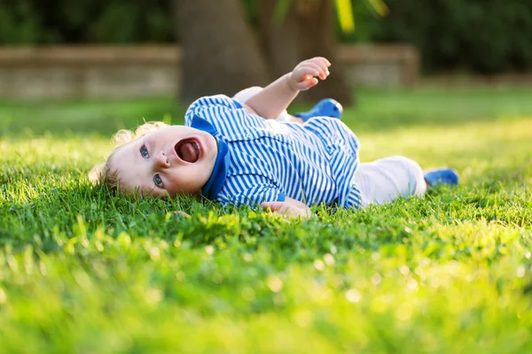 Pequena menina bonita muito feliz deitado na grama e gritos — Fotografia de Stock