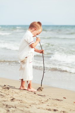 Küçük çocuk kumsalda açık sopa ile oynamak,