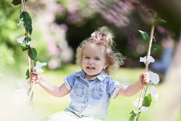 Liten söt flicka gungar på gungbräda i sommaren park, stående utomhus — Stockfoto