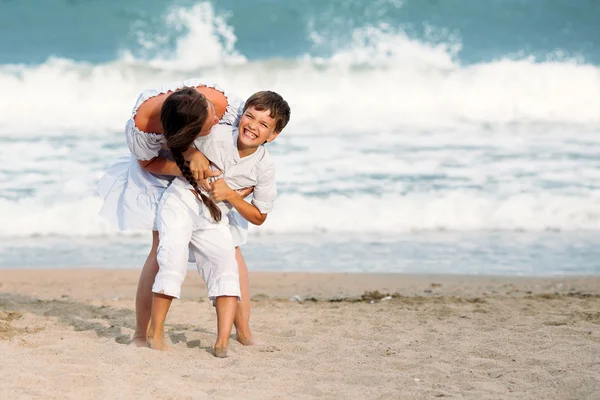 Cheerful, happy mother and son playing on beach — Stock Photo, Image