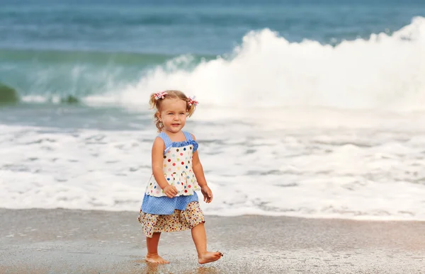Kleines schönes glückliches Mädchen, das am Strand geht — Stockfoto