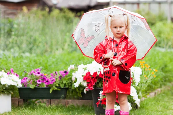 Ernsthafte nachdenkliche hübsche kleine Mädchen in rotem Regenmantel mit Regenschirm — Stockfoto