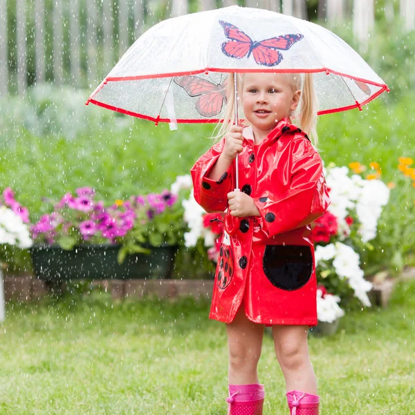 Ernsthafte nachdenkliche hübsche kleine Mädchen in rotem Regenmantel mit Regenschirm — Stockfoto