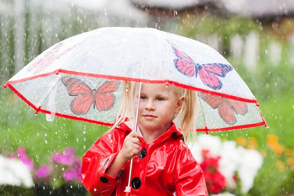 Ernstig nadenkend vrij klein meisje in de rode regenjas met paraplu — Stockfoto