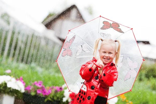 Fröhlicher Spaß hübsches kleines Mädchen in rotem Regenmantel mit Regenschirm spazieren im Park Sommer — Stockfoto