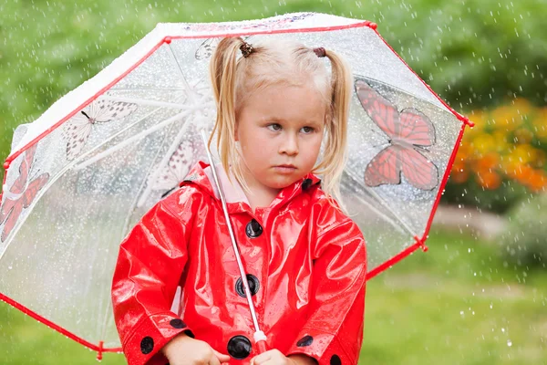 Ernstig nadenkend vrij klein meisje in de rode regenjas met paraplu — Stockfoto