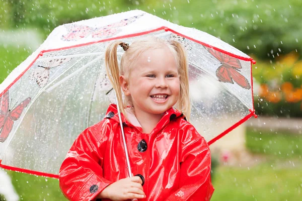 Щасливі веселощі гарненька дівчинка в червоному плащі з парасолькою, що йде в парку літо — стокове фото