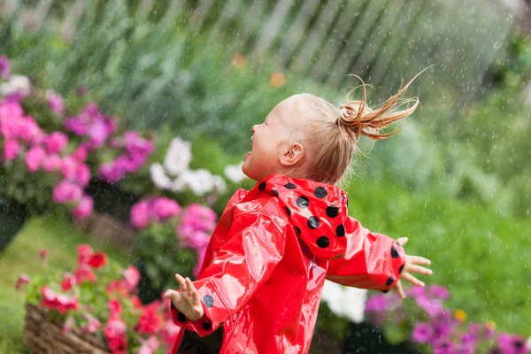 Fröhlicher Spaß hübsches kleines Mädchen in rotem Regenmantel mit Regenschirm spazieren im Park Sommer — Stockfoto