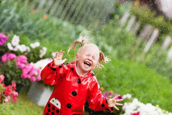 Feliz diversión bonita niña en impermeable rojo con paraguas caminando en verano parque —  Fotos de Stock