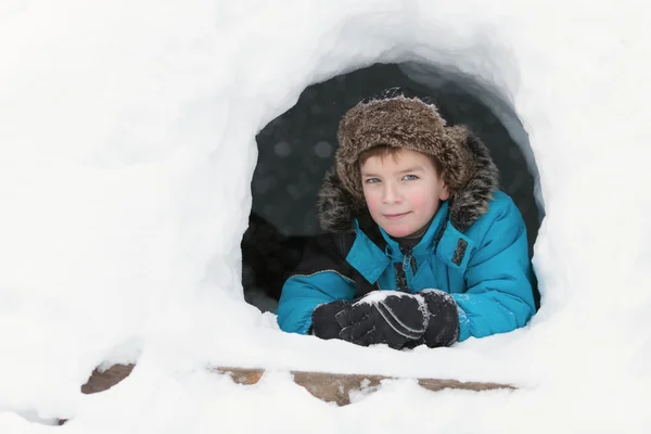 Ruddy beautiful boy in winter clothes peeking out of snow mountain, — Stock Photo, Image