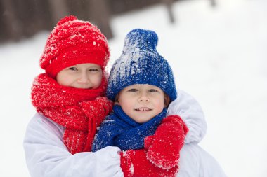 Mutlu erkek kardeşi ve kız kardeşi kış ormanda yürüyüş kostümleri kardan adam,