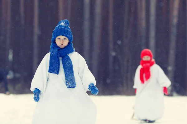 Gelukkig broer en zus in kostuums sneeuwpop wandelen in winter woud, — Stockfoto