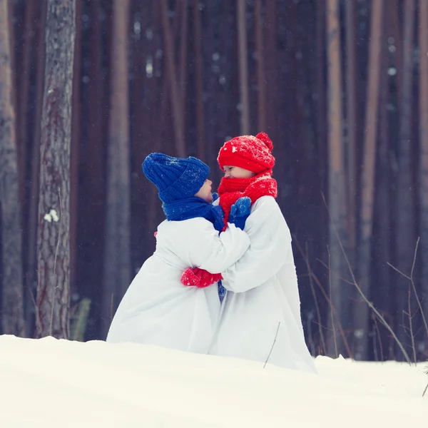 Feliz hermano y hermana en trajes muñeco de nieve caminando en el bosque de invierno , — Foto de Stock