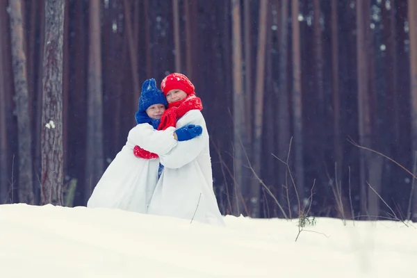 幸せな兄と妹の衣装雪だるま冬の森を歩く, — ストック写真