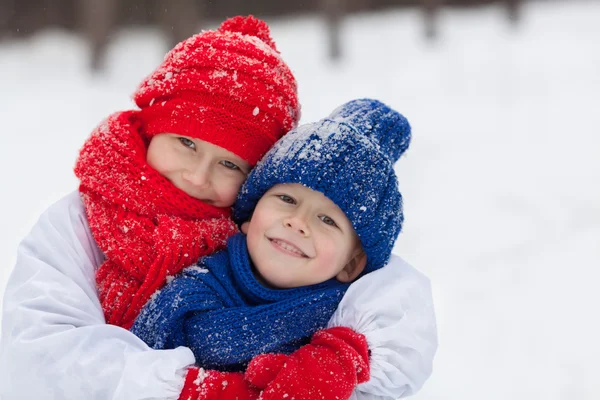 Feliz hermano y hermana en trajes muñeco de nieve caminando en el bosque de invierno , — Foto de Stock