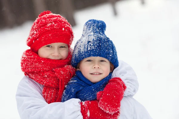 Mutlu erkek kardeşi ve kız kardeşi kış ormanda yürüyüş kostümleri kardan adam,