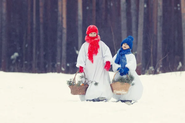 Feliz hermano y hermana en trajes muñeco de nieve caminando en el bosque de invierno , —  Fotos de Stock