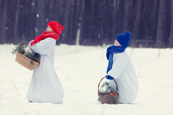 Mutlu erkek kardeşi ve kız kardeşi kış ormanda yürüyüş kostümleri kardan adam, — Stok fotoğraf