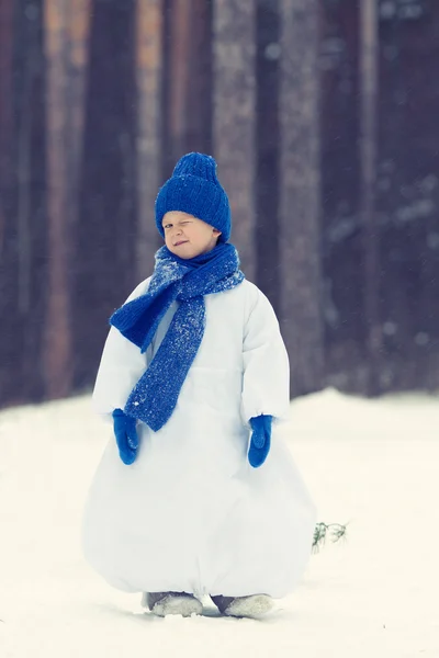 Felice ragazzo in costume pupazzo di neve che cammina nella foresta invernale , — Foto Stock