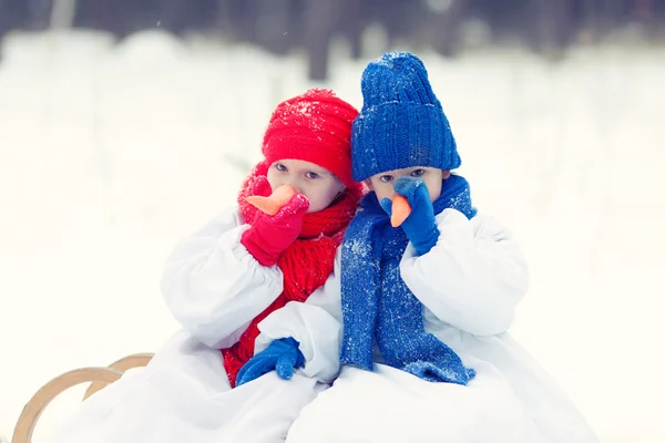 Feliz hermano y hermana en trajes muñeco de nieve caminando en el bosque de invierno — Foto de Stock