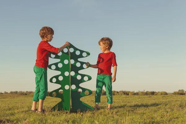 Irmãos felizes estão brincando com árvore de papel — Fotografia de Stock