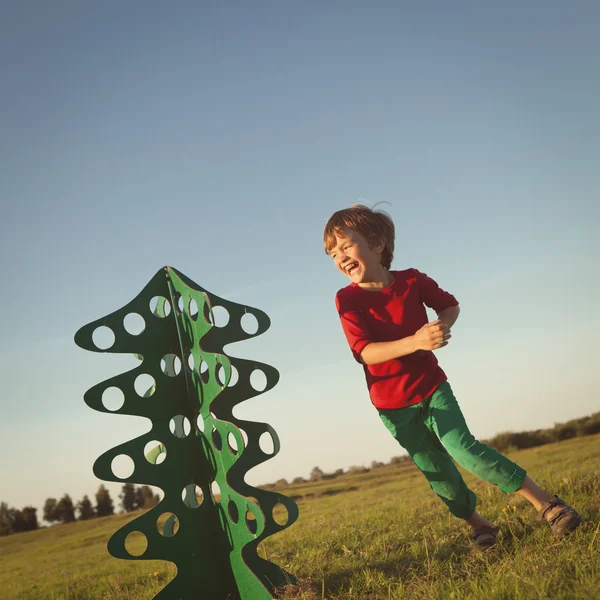 Menino feliz brincando com árvore de papel — Fotografia de Stock
