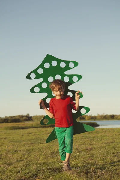 Menino feliz brincando com árvore de papel — Fotografia de Stock