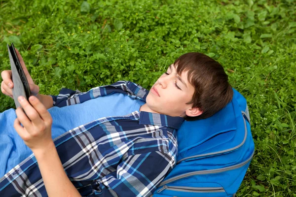 Adolescente feliz deitado na grama no parque — Fotografia de Stock