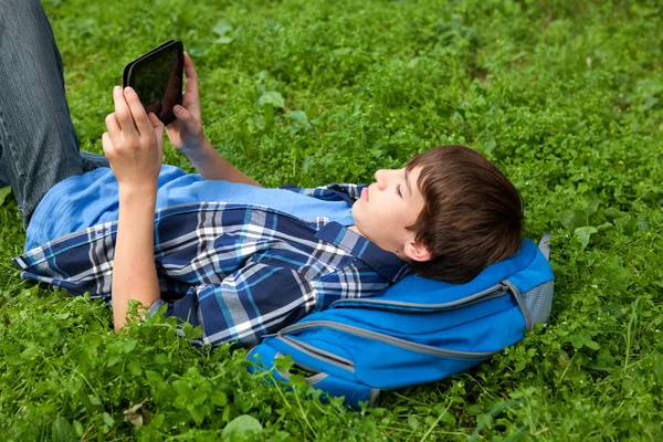 Adolescente feliz deitado na grama no parque — Fotografia de Stock