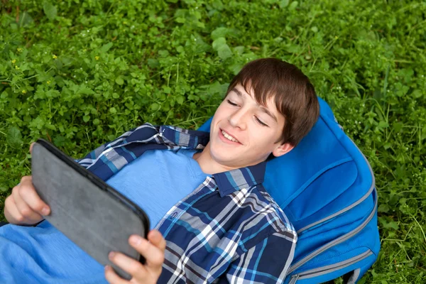 Adolescente feliz deitado na grama no parque — Fotografia de Stock
