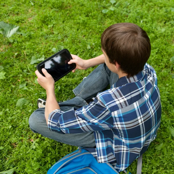 Счастливый подросток сидит на траве в парке — стоковое фото