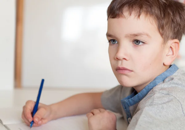 Serious pensive pupil sits at desk — Stock Photo, Image