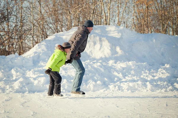 Happy fun otce a syna naučit se bruslit, zima, venkovní — Stock fotografie