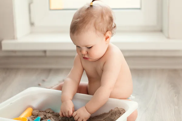 Little girl playing with sand on floor — Stock Photo, Image