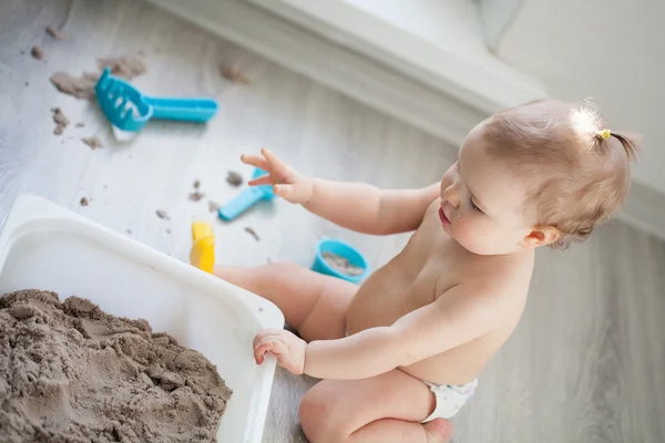 Küçük kız yerde kum ile oynamak — Stok fotoğraf