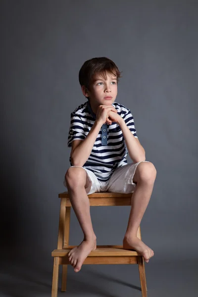 Portrait of serious pensive sad teenager on chair — Stock Photo, Image