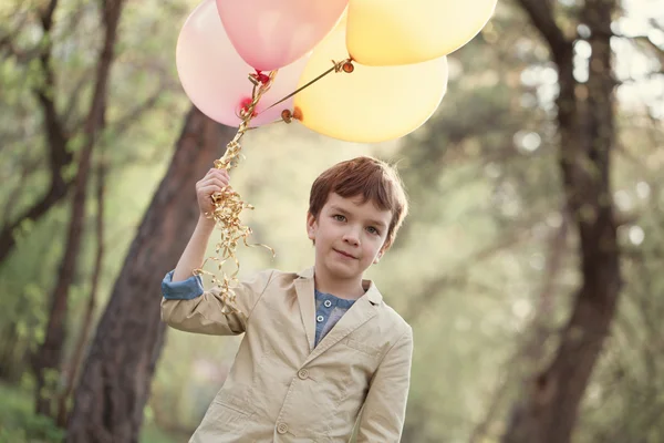 Niño feliz con globos de colores en celebración —  Fotos de Stock