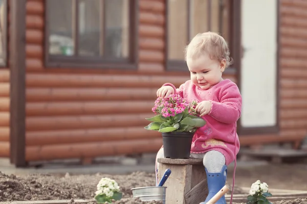 Niedliche Baby-Mädchen in rosa Kleid legt Blumen — Stockfoto