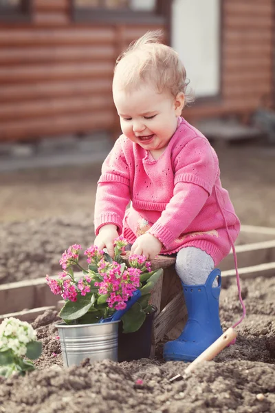 Bonito bebê menina no vestido rosa coloca flores — Fotografia de Stock